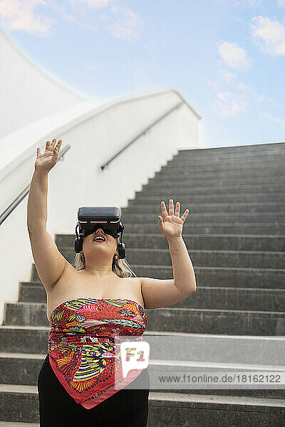 Young woman wearing virtual reality simulator in front of staircase