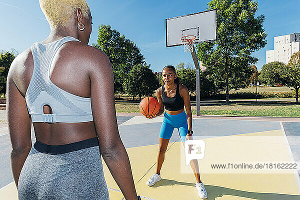 Sportswoman playing with basketball friend in court