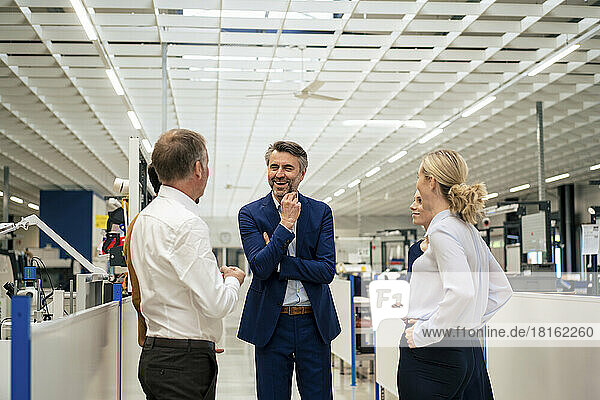 Happy mature businessman discussing with colleagues at industry