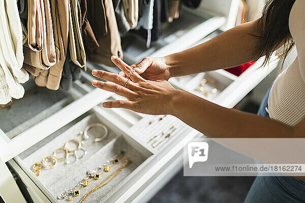 Woman choosing jewelry standing by drawer at home