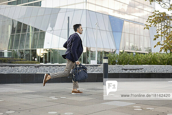 Businessman with bag running in front of building