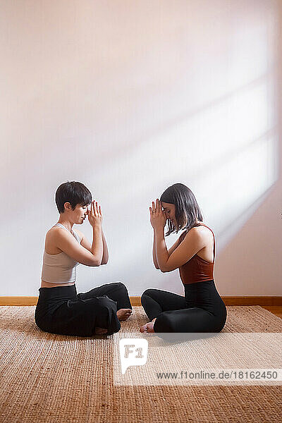 Freunde praktizieren gemeinsam Yoga voreinander