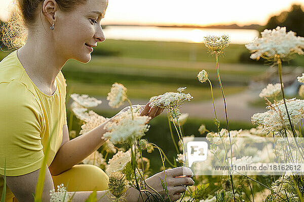 Smiling woman looking at white wildflower