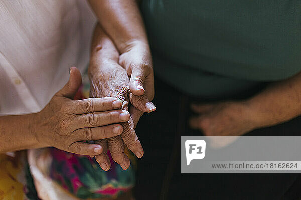 Frau streichelt die Hand einer älteren Mutter