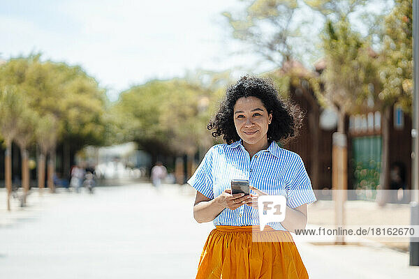 Smiling woman with smart phone on sunny day
