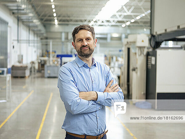 Businessman with arms crossed standing in industry