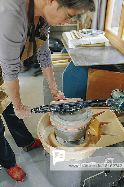 Potter making ceramics on pottery wheel at workshop