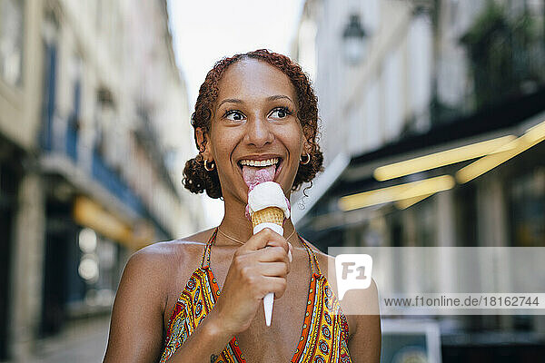 Happy young woman licking ice cream