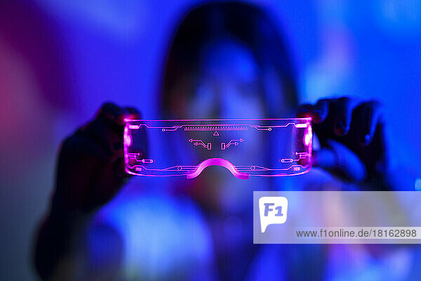 Hands of woman holding LED smart glasses