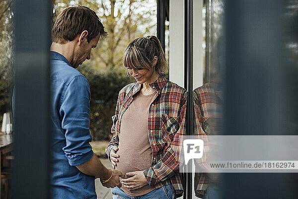 Mann blickt auf schwangeren Bauch einer Frau