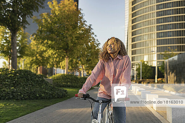 Nachdenkliche junge Frau fährt Fahrrad auf Fußweg in der Stadt