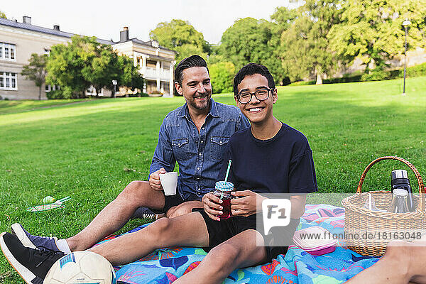 Happy boy enjoying picnic with father sitting in lawn