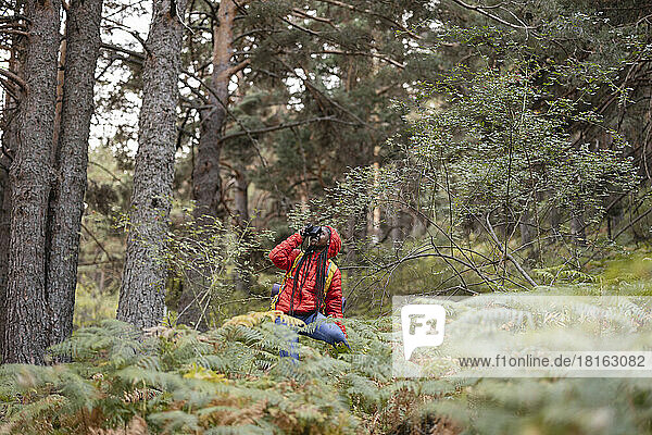 Young woman photographing through camera in forest