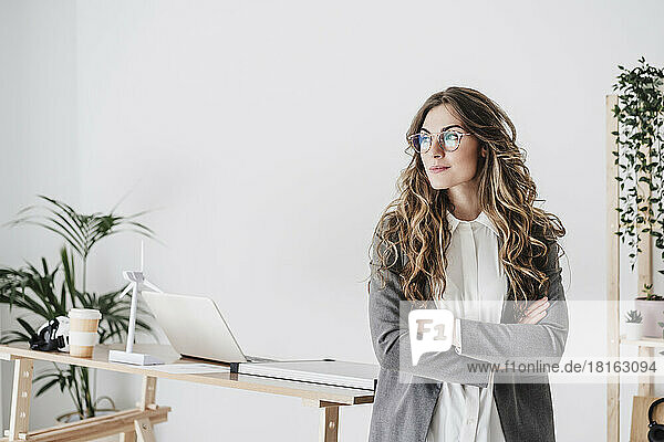 Confident businesswoman standing in office with arms crossed