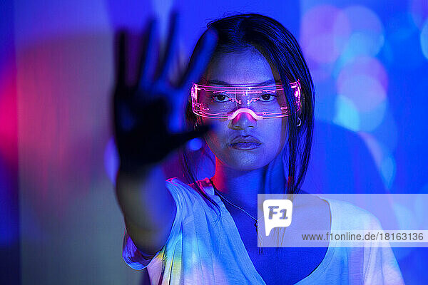 Junge Frau mit futuristischer Brille zeigt Handfläche