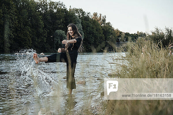 Happy young woman splashing water in lake