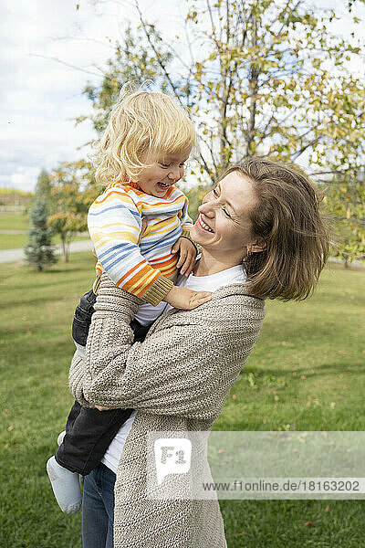 Glückliche Mutter trägt ihren Sohn im Park