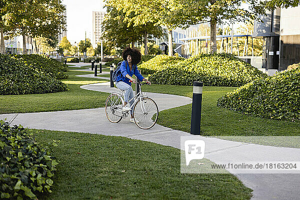 Smiling woman with bicycle on footpath in park