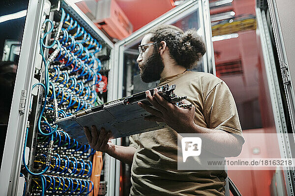 Technician looking at cables holding machine part in server room