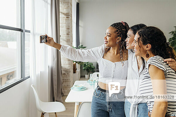 Smiling woman taking selfie with friends at home