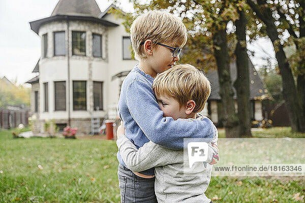 Siblings hugging each other in back yard