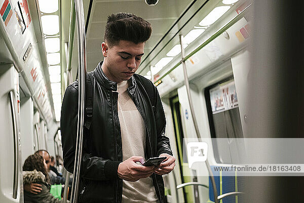 Young man using smart phone in subway train