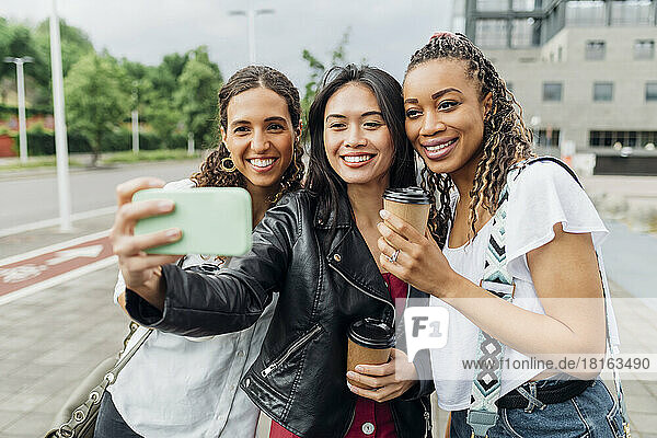 Lächelnde Frau macht Selfie mit Freunden auf dem Smartphone