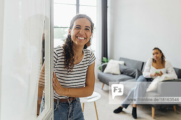 Happy young woman opening door at home