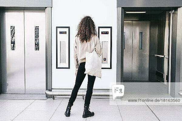 Woman with curly hair standing in front of elevator