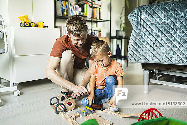 Vater und Sohn spielen zu Hause zusammen mit der Miniatureisenbahn