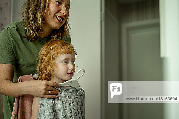 Mother and daughter choosing dress at home