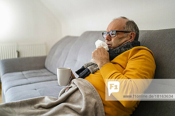 Man coughing sitting on sofa in living room