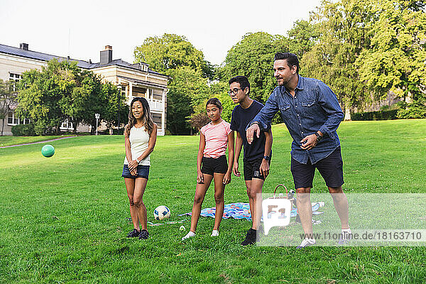 Multiracial family enjoying boules on grass in lawn