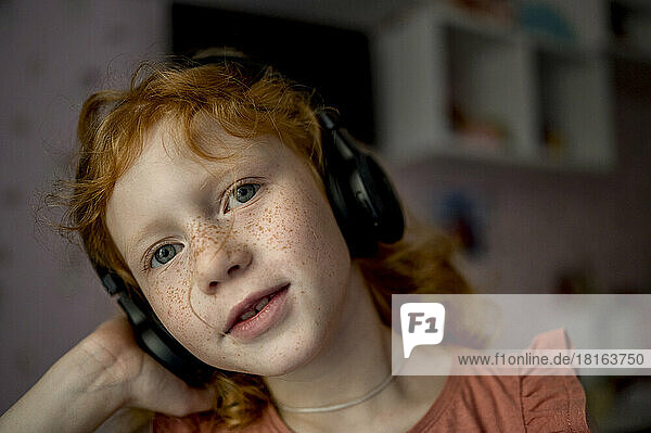 Girl with wireless headphones listening to music at home