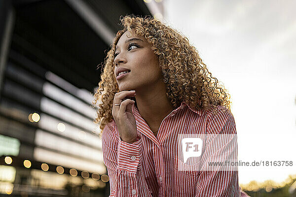 Young woman with hand on chin contemplating at sunset