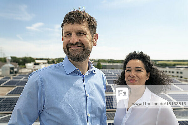 Smiling businesswoman with colleague in front of solar panels