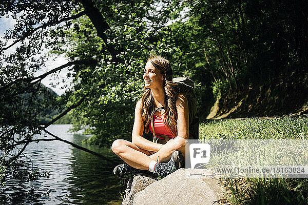 Happy woman sitting cross-legged near Lake Levico