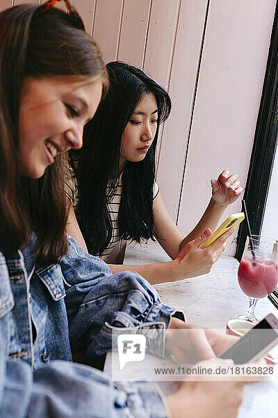 Lesbisches Paar benutzt Smartphones im Café