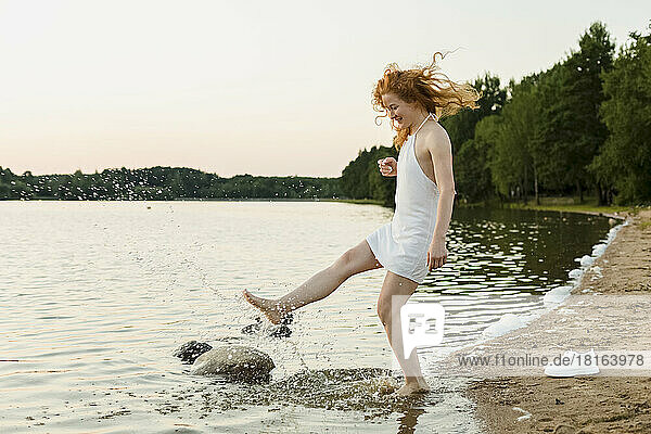 Happy woman splashing water at beach