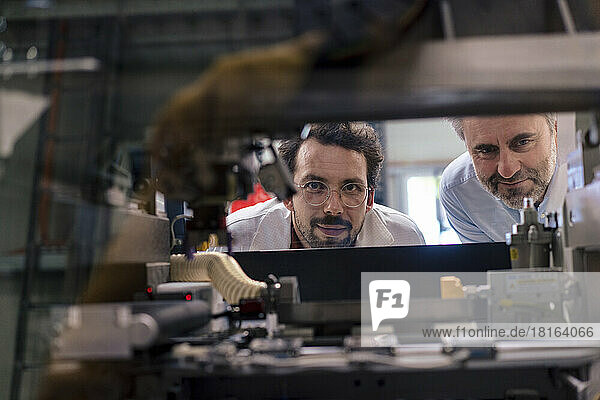 Mature businessman with colleague examining machinery at industry
