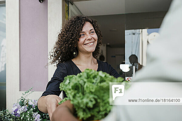 Glückliche junge Geschäftsfrau  die Gemüse für das Restaurant liefert
