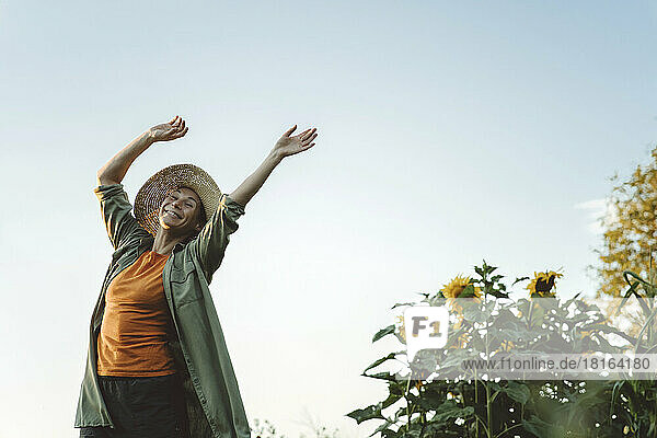 Glückliche Frau mit Hut tanzt im Garten