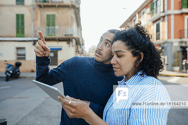 Young freelancer talking to colleague using tablet PC on road