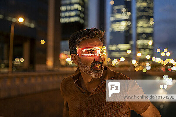 Excited businessman wearing smart glasses in city at night