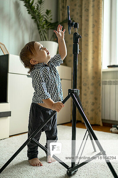 Baby boy reaching for smart phone on tripod at home