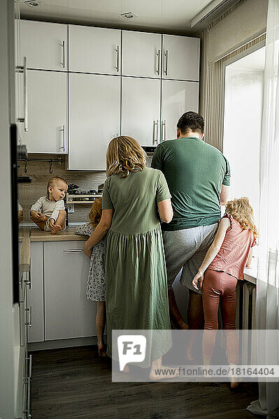 Mutter und Vater mit Kindern stehen in der Küche