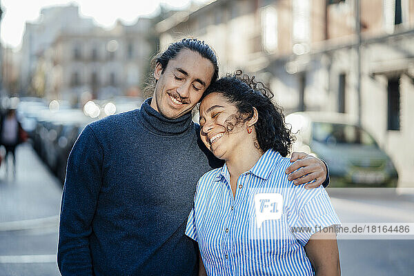 Lächelndes Paar träumt gemeinsam mit geschlossenen Augen auf der Straße