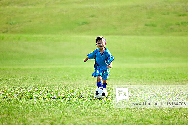 Japanese kid playing soccer at a city park