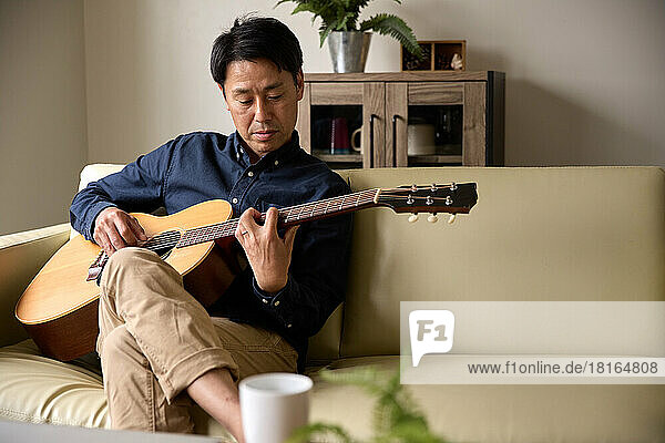Japanese man playing acoustic guitar
