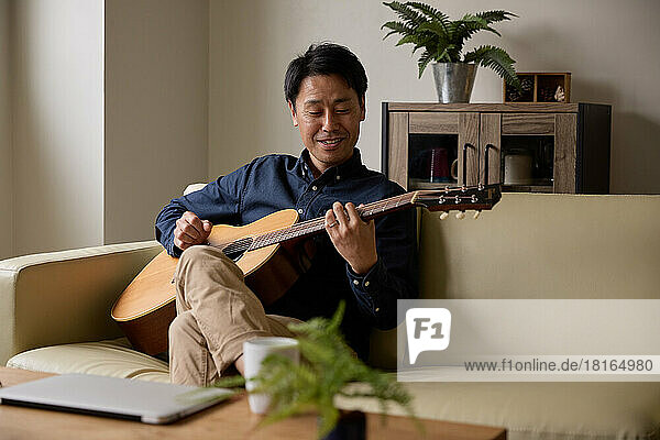 Japanischer Mann spielt akustische Gitarre